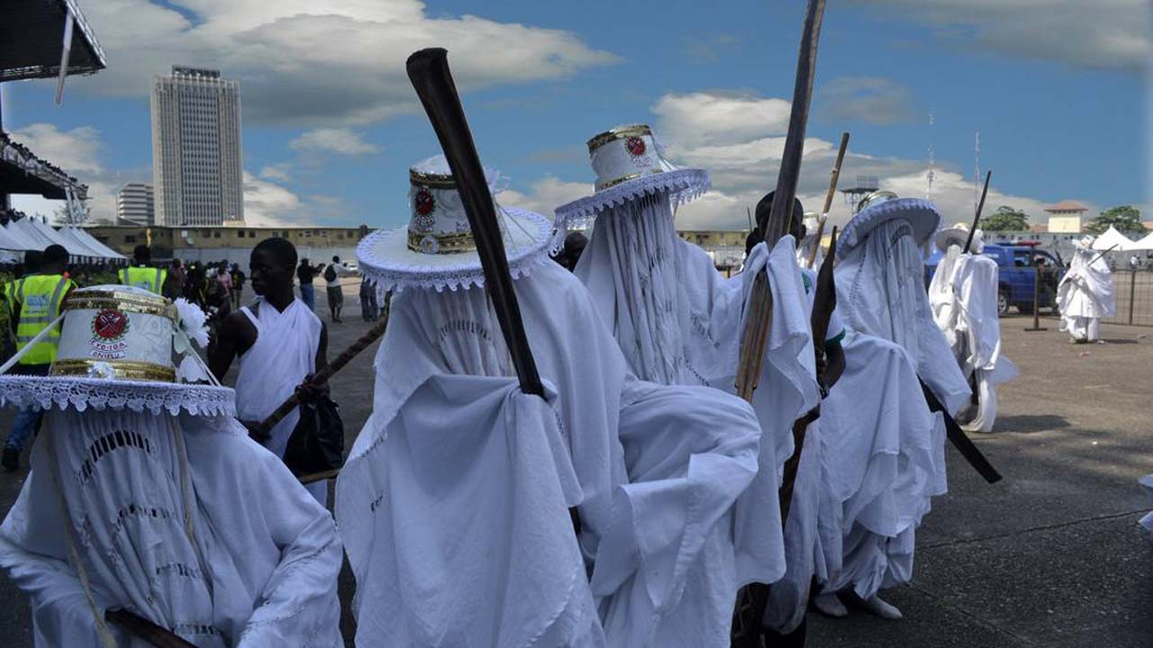 Eyo Masquerade in full traditional regalia wielding large ceremonial sticks called Opabata.